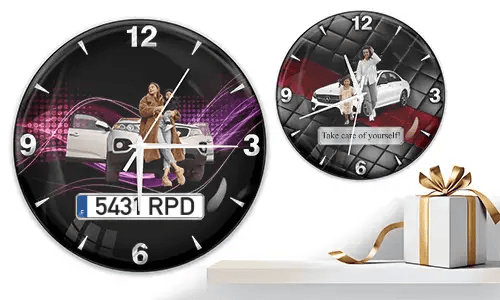 Two wall clocks with family car scenes: left with woman and child at white SUV over purple waves, right with white car and quilted red-black background