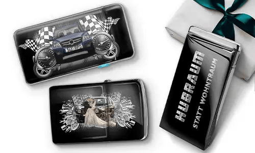 Three black wallets with car-themed designs and checkered flags, set against a white background. One shows a car with wheels, another features a couple, and one has 