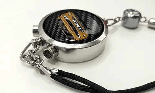 Round car key fob with carbon fiber face, buttons labeled LOCK and UNLOCK, braided black cord attached
