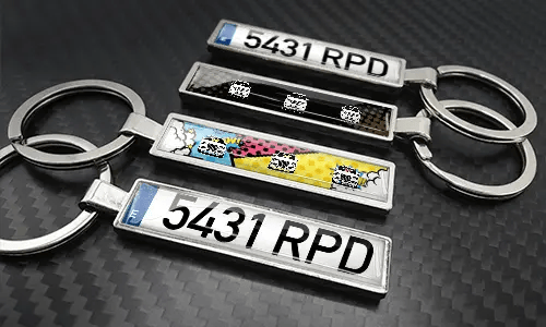 Sleutelhangers in stripstijl met kentekenplaat, gerangschikt op een koolstoftextuur met kleurrijke autographics